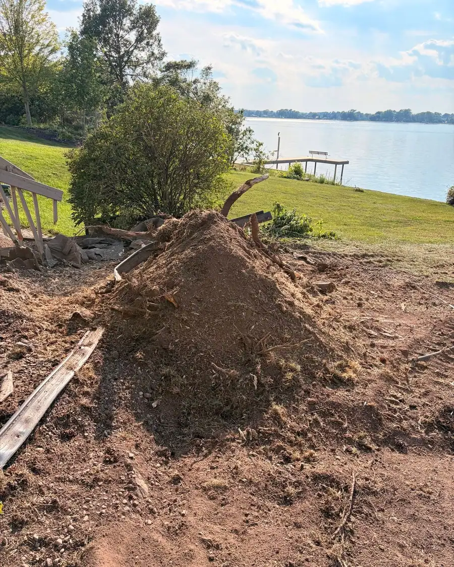 A pile of grindings left on site beside a lake after a stump was ground